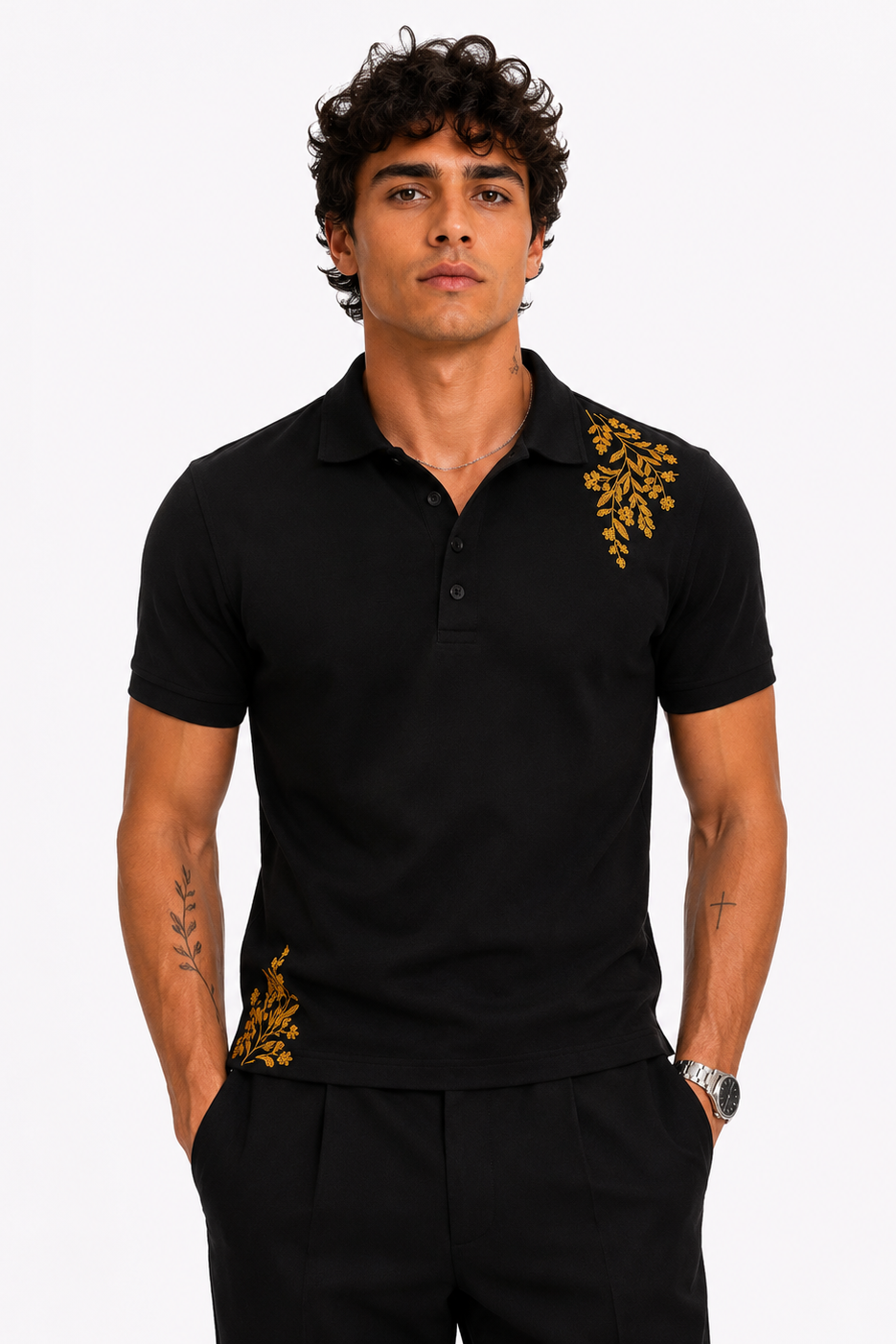 A man wearing a black short-sleeve polo shirt with gold embroidered leaf patterns on the shoulders and waist, paired with black trousers, against a light gray background.